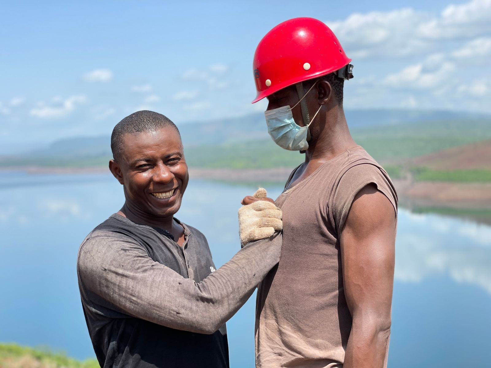 Two men smiling together outdoors on a work site