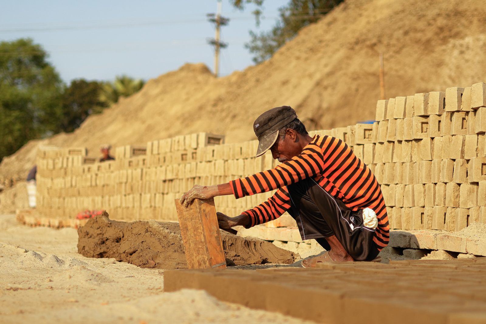 Worker arranging bricks laid out to dry in the open