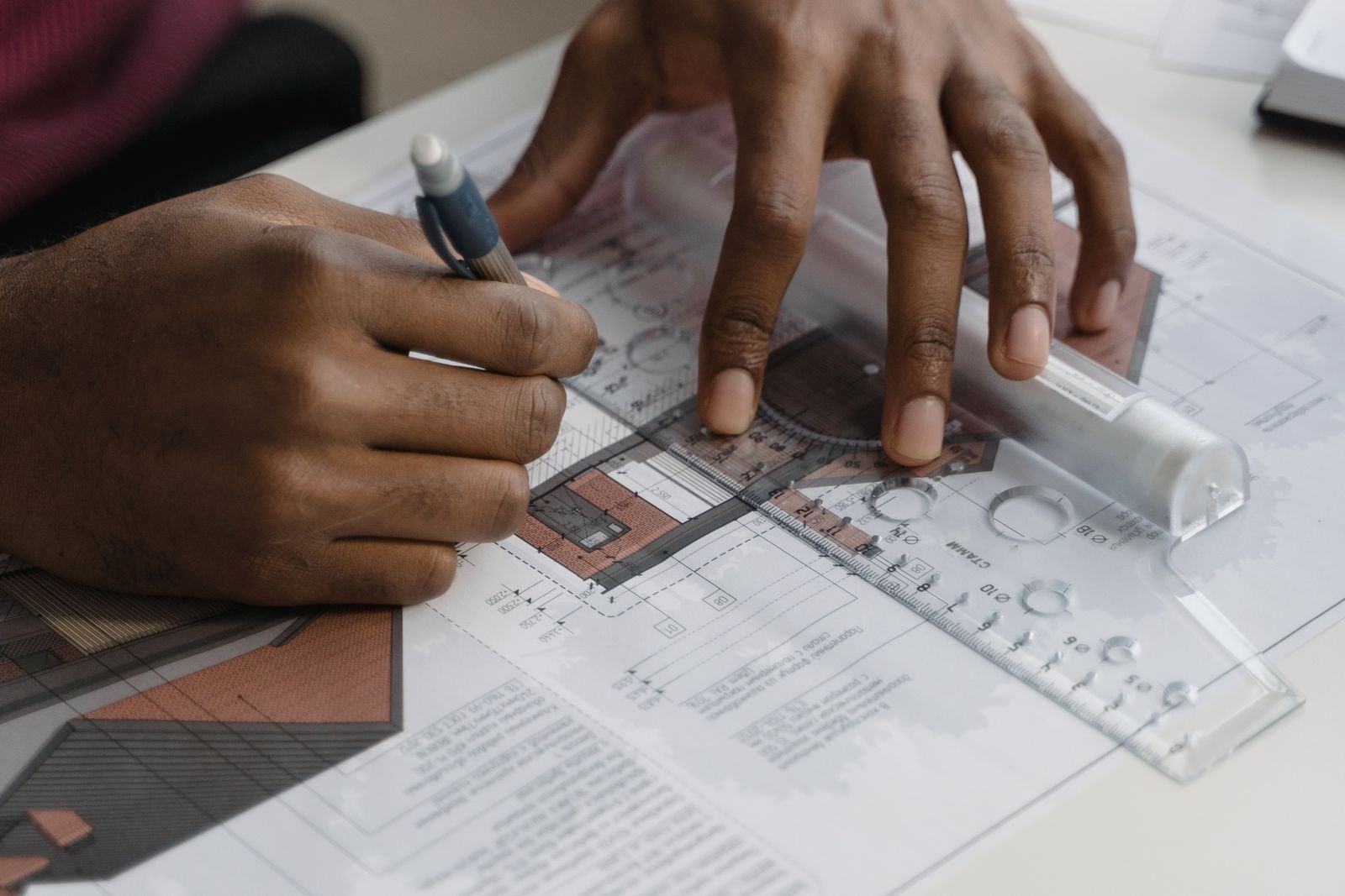 Hands marking up construction drawings with a pen