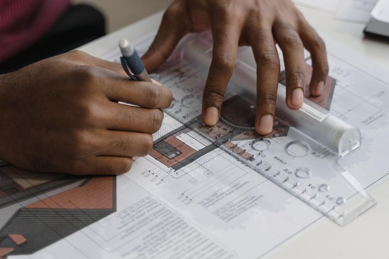 Hands marking up construction drawings with a pen