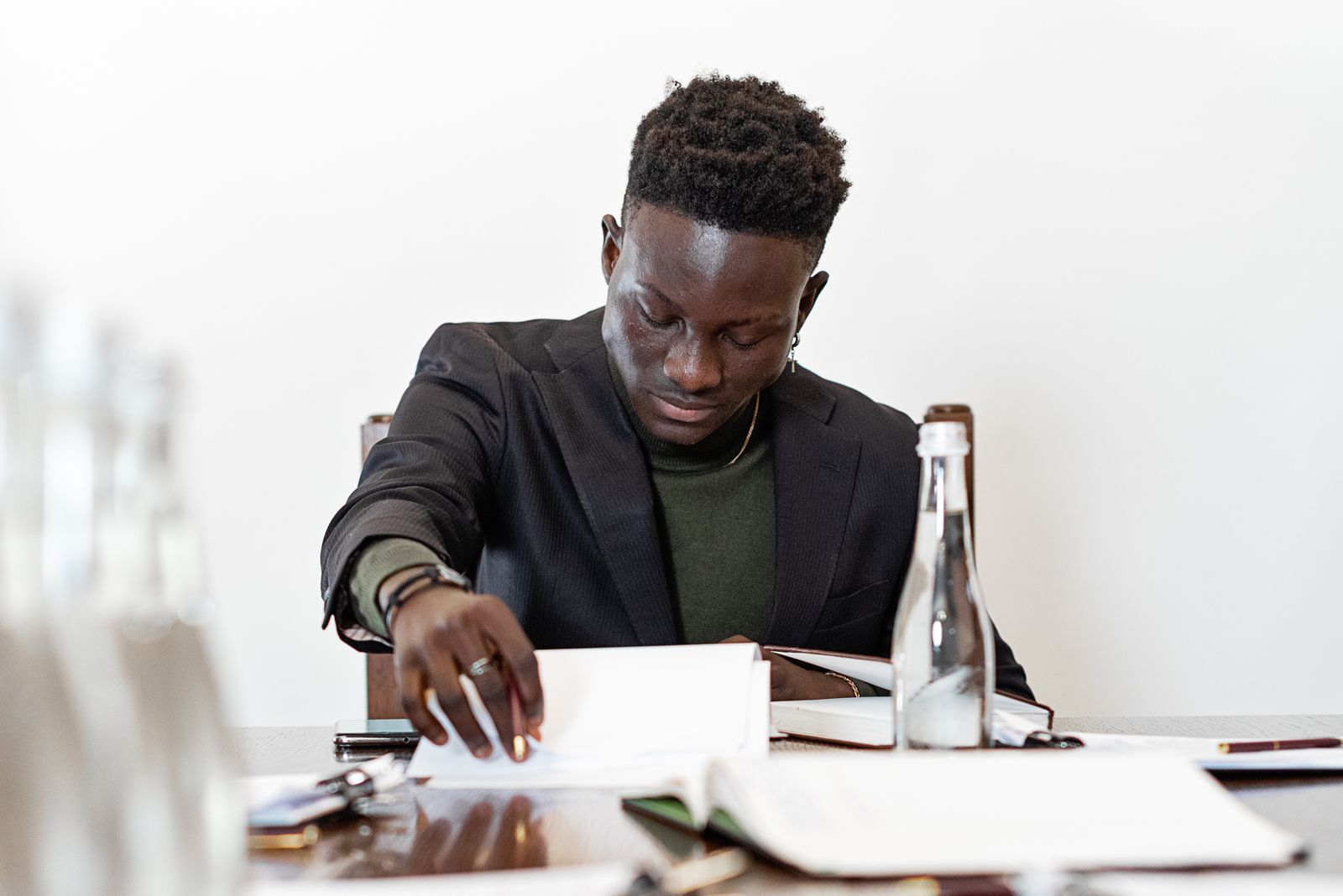 Black businessman wearing a blazer, intently reading documents at a table