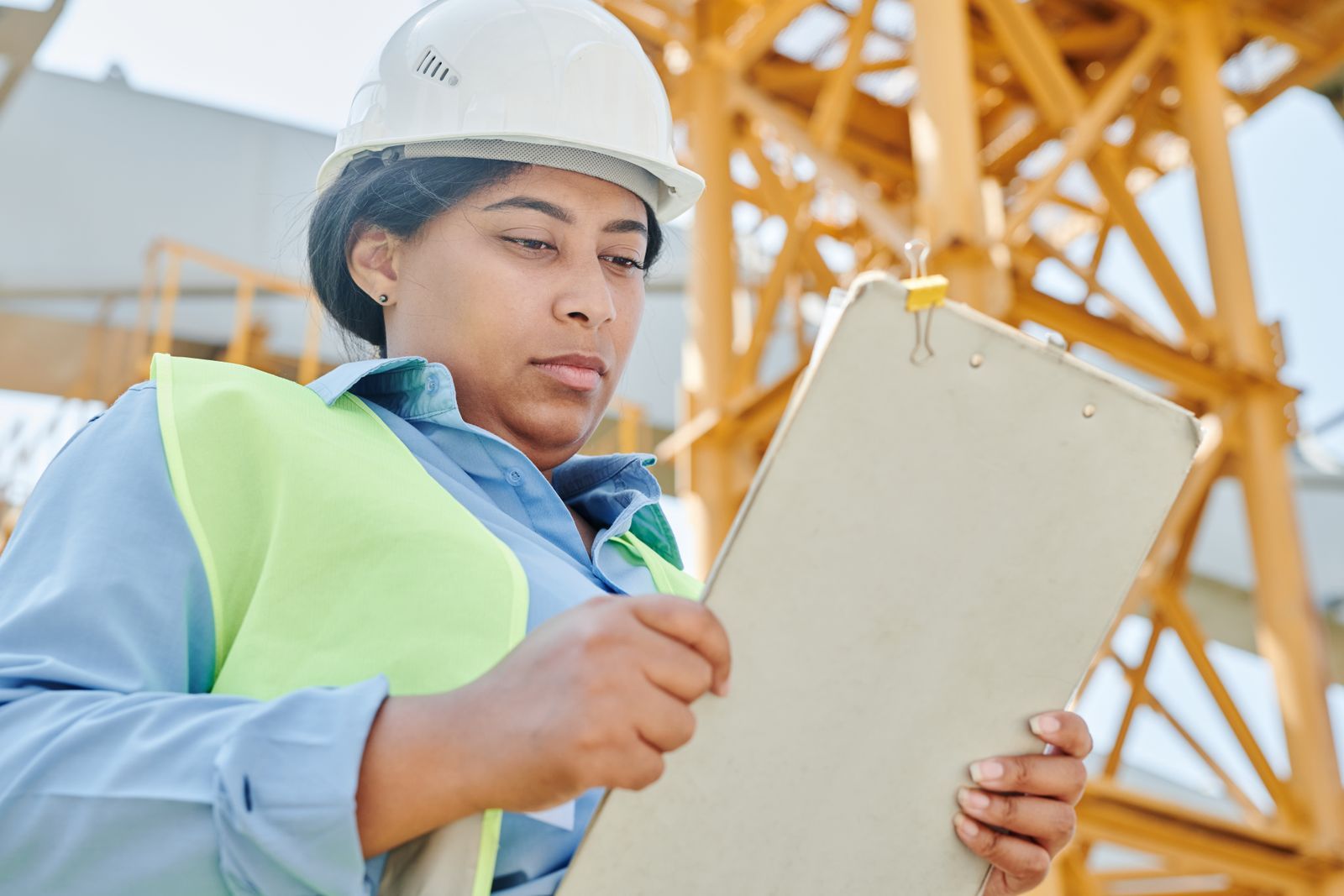Female construction worker inspecting site with clipboard and helmet