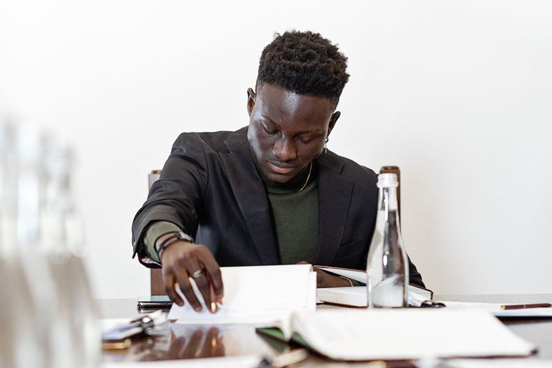 Black businessman wearing a blazer, intently reading documents at a table