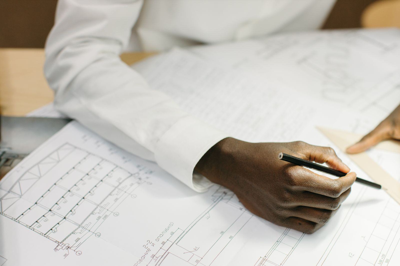 Hand holding a pencil over construction drawings