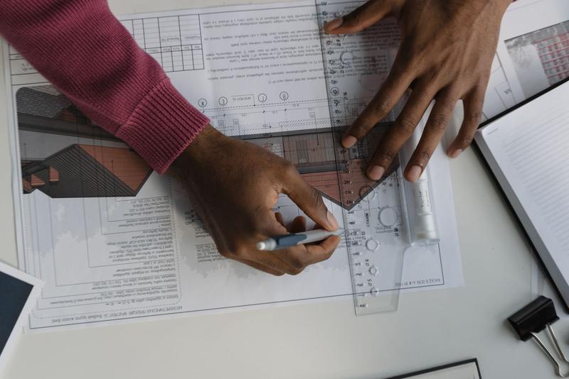 Hands drawing on construction plans with a ruler