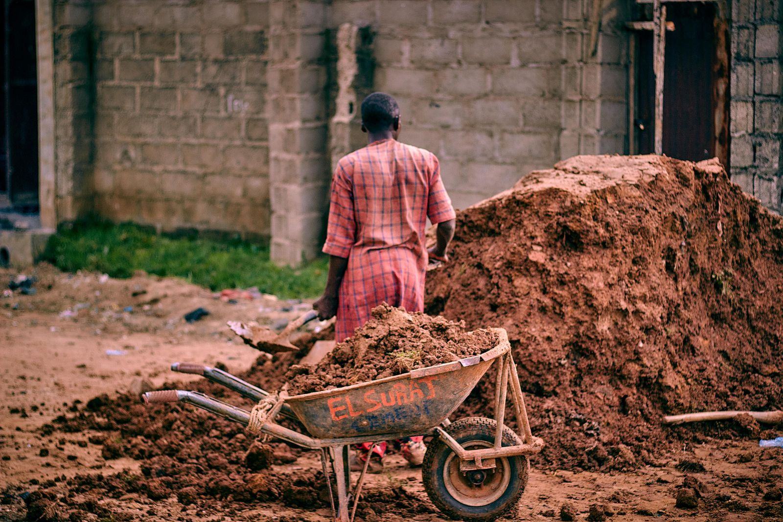 Worker moving excavated soil with a wheelbarrow on site