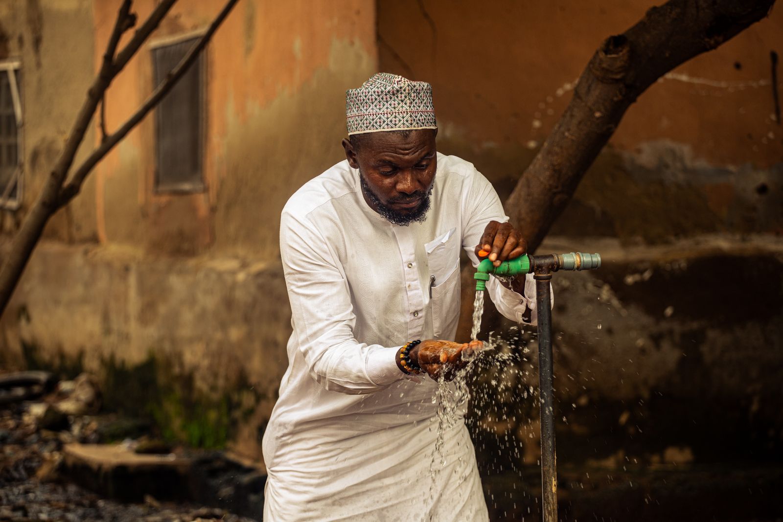 A man washing hands under faucet outdoors in Nigeria
