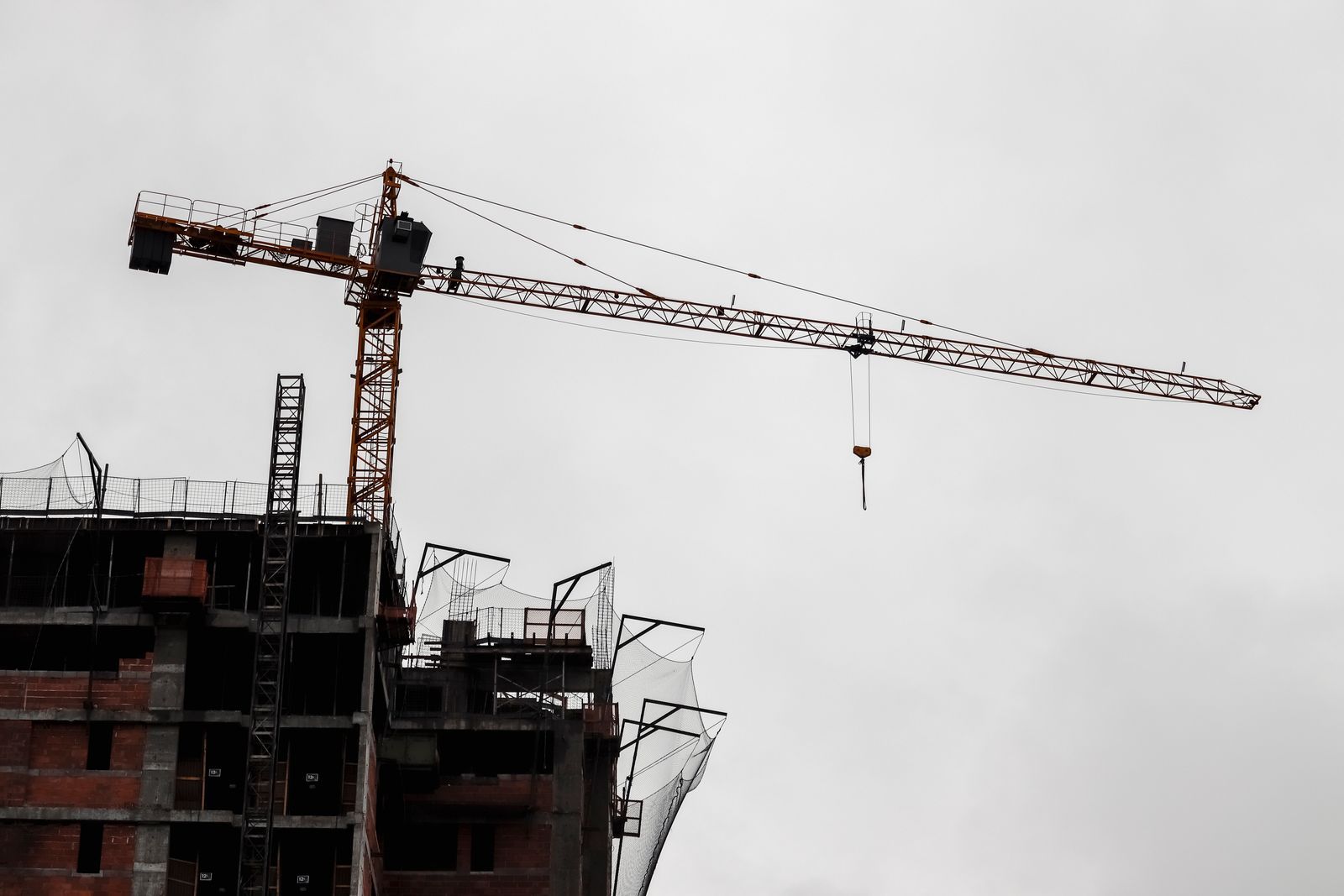 Building under construction with a tower crane under a grey sky