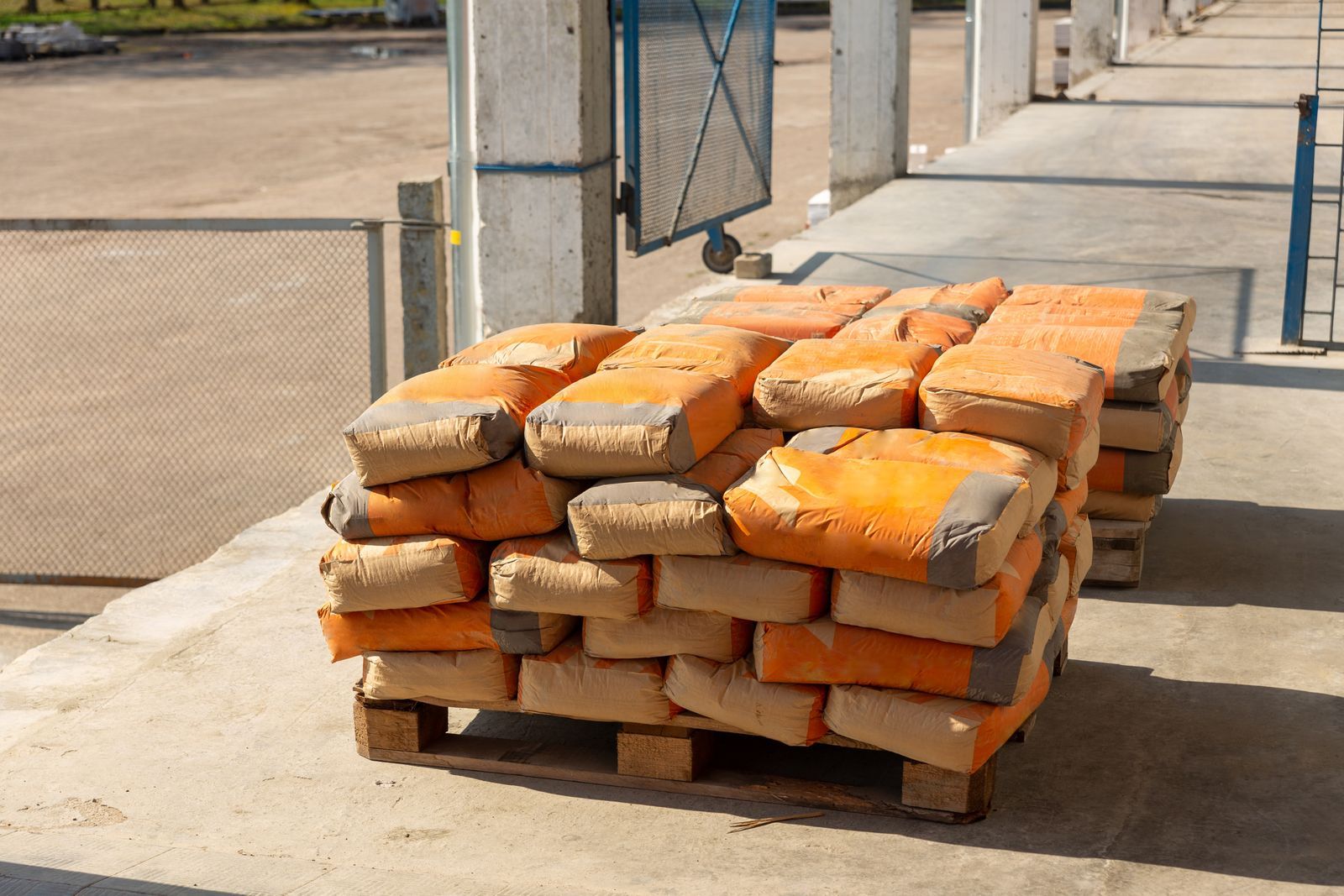 Pile of orange cement bags on a wooden pallet in an industrial setting