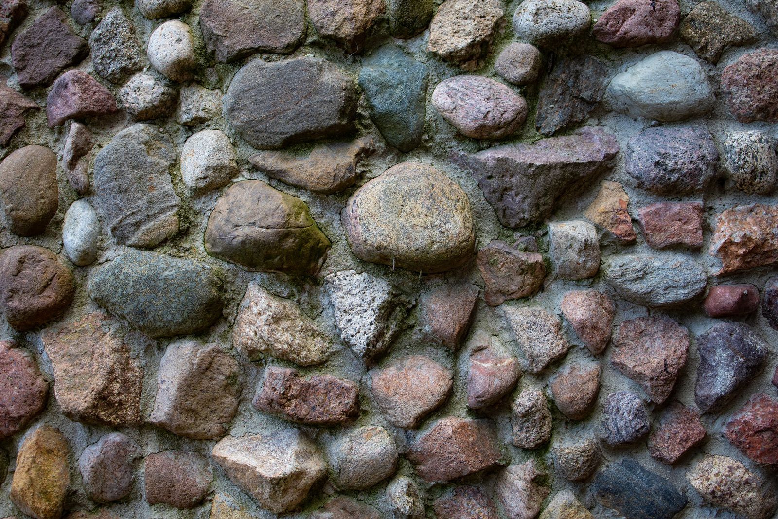 Close-up of a textured stone wall with colorful rocks in various shapes and sizes
