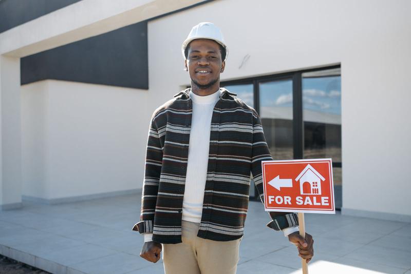 Man standing next to a property for sale sign