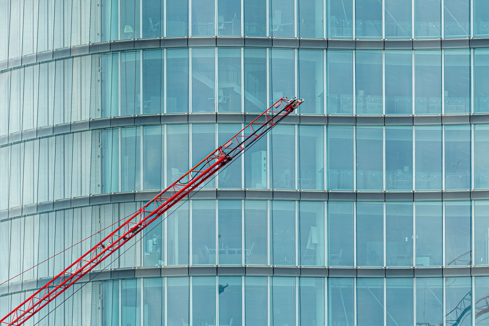 Glass office building facade with a crane during construction