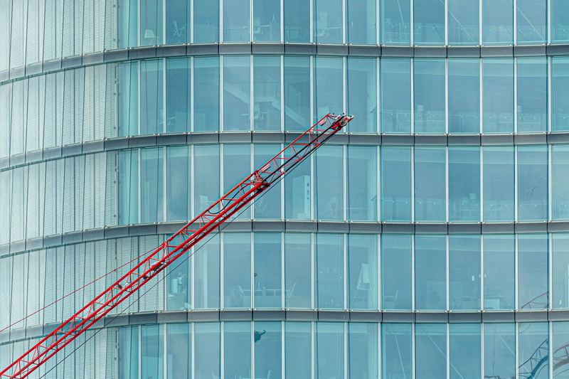 Glass office building facade with a crane during construction