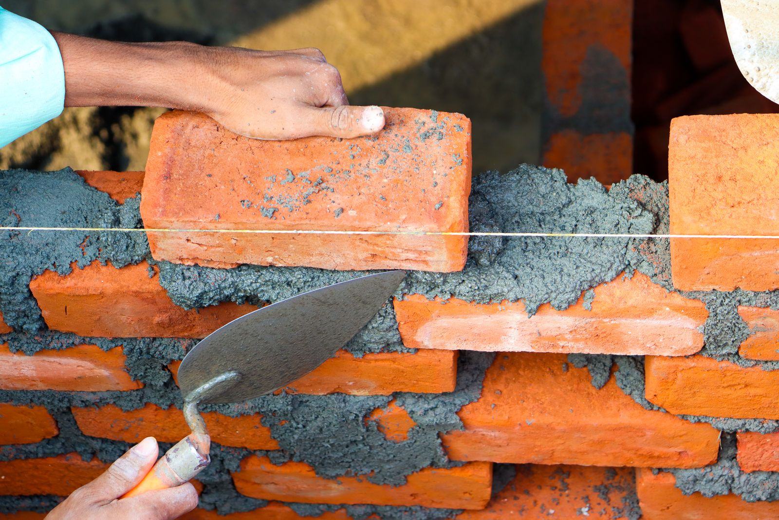 Bricklayer laying clay bricks with mortar