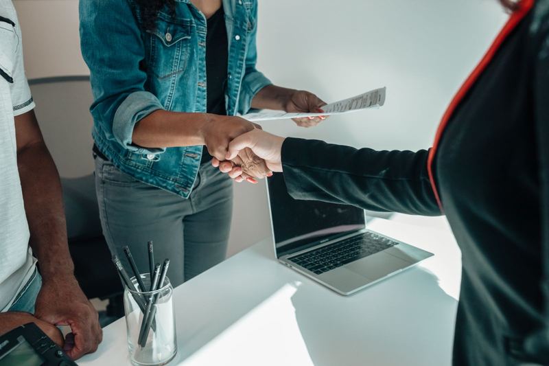 Two people shaking hands over a desk