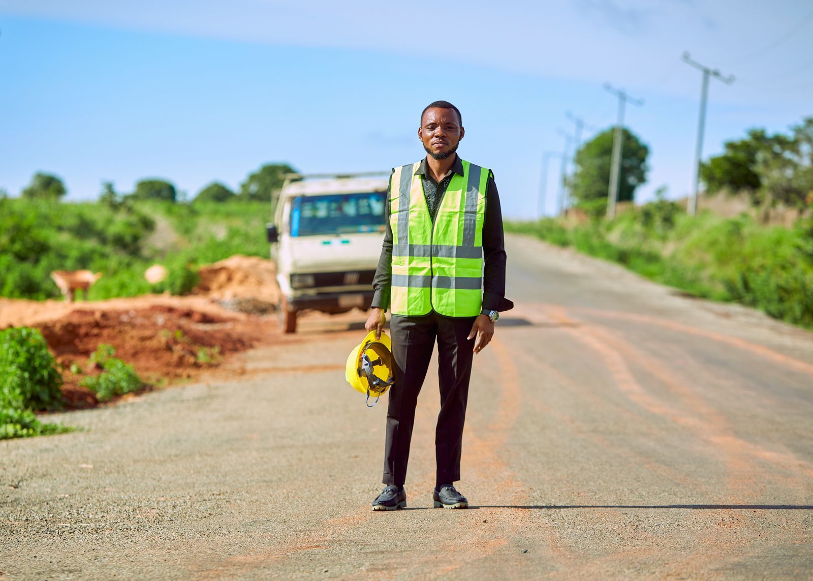 Engineer in a safety vest on a road beside a construction site