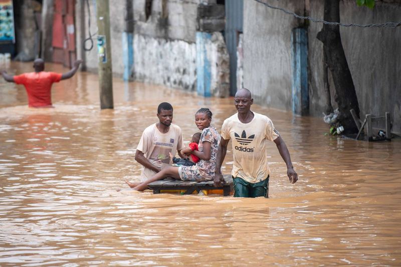 People wading through a flooded street after heavy rain
