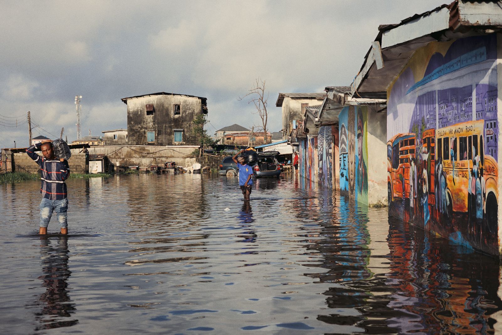 People wading through a flooded street lined with houses