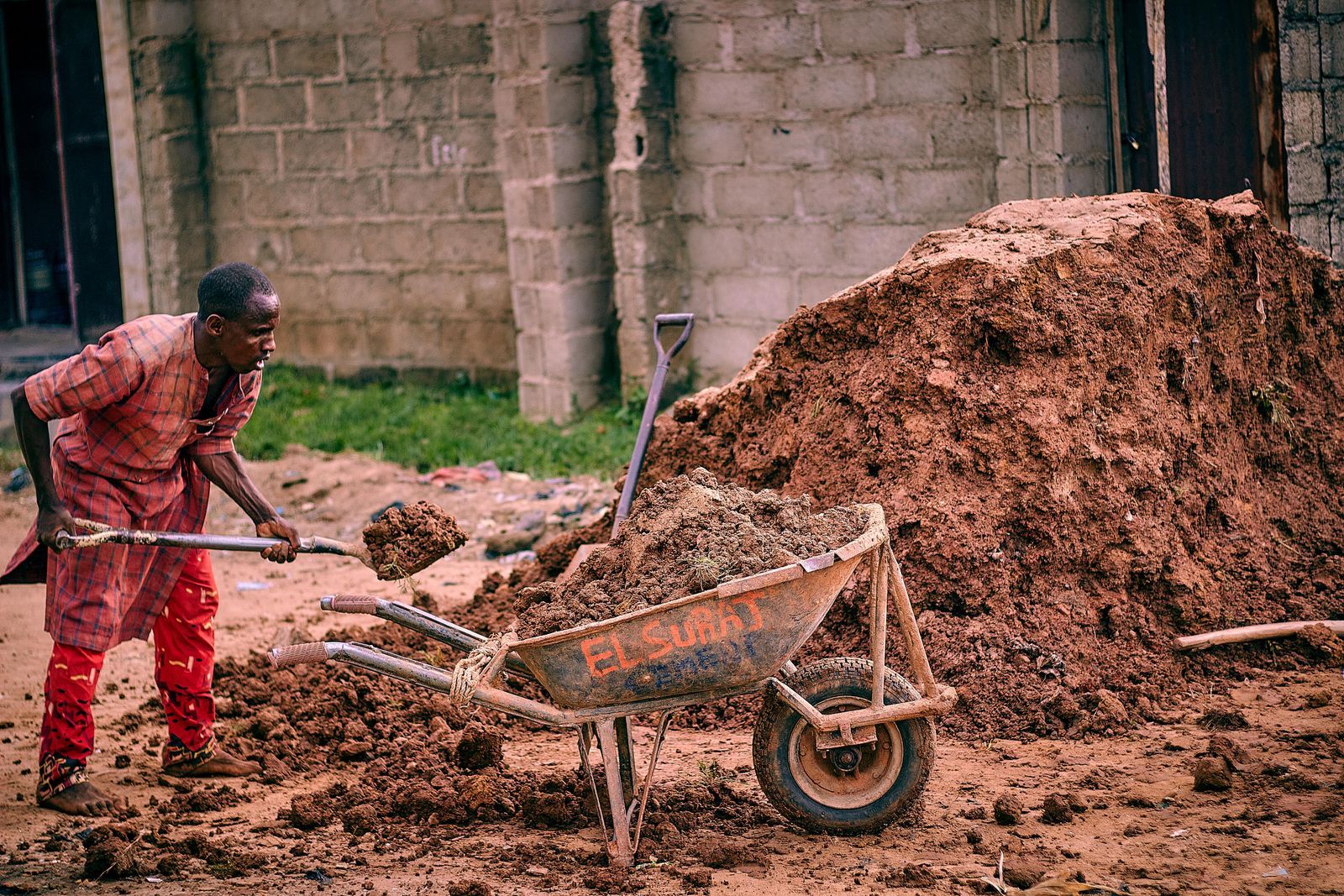 Worker moving soil with a wheelbarrow on a building plot