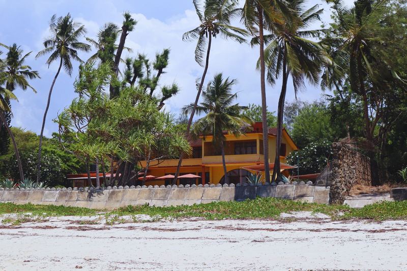 A beachfront house in Mombasa, Kenya, surrounded by palm trees and lush greenery