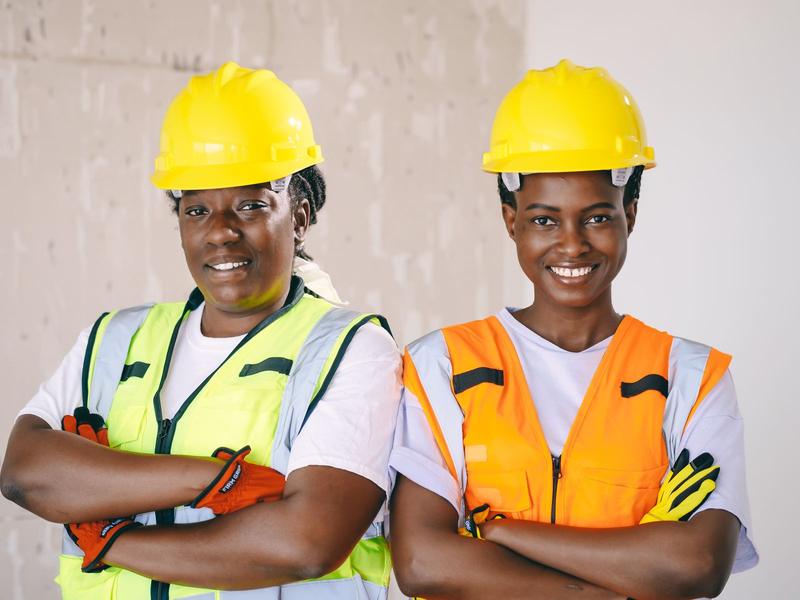 Two smiling women engineers in hard hats and safety vests