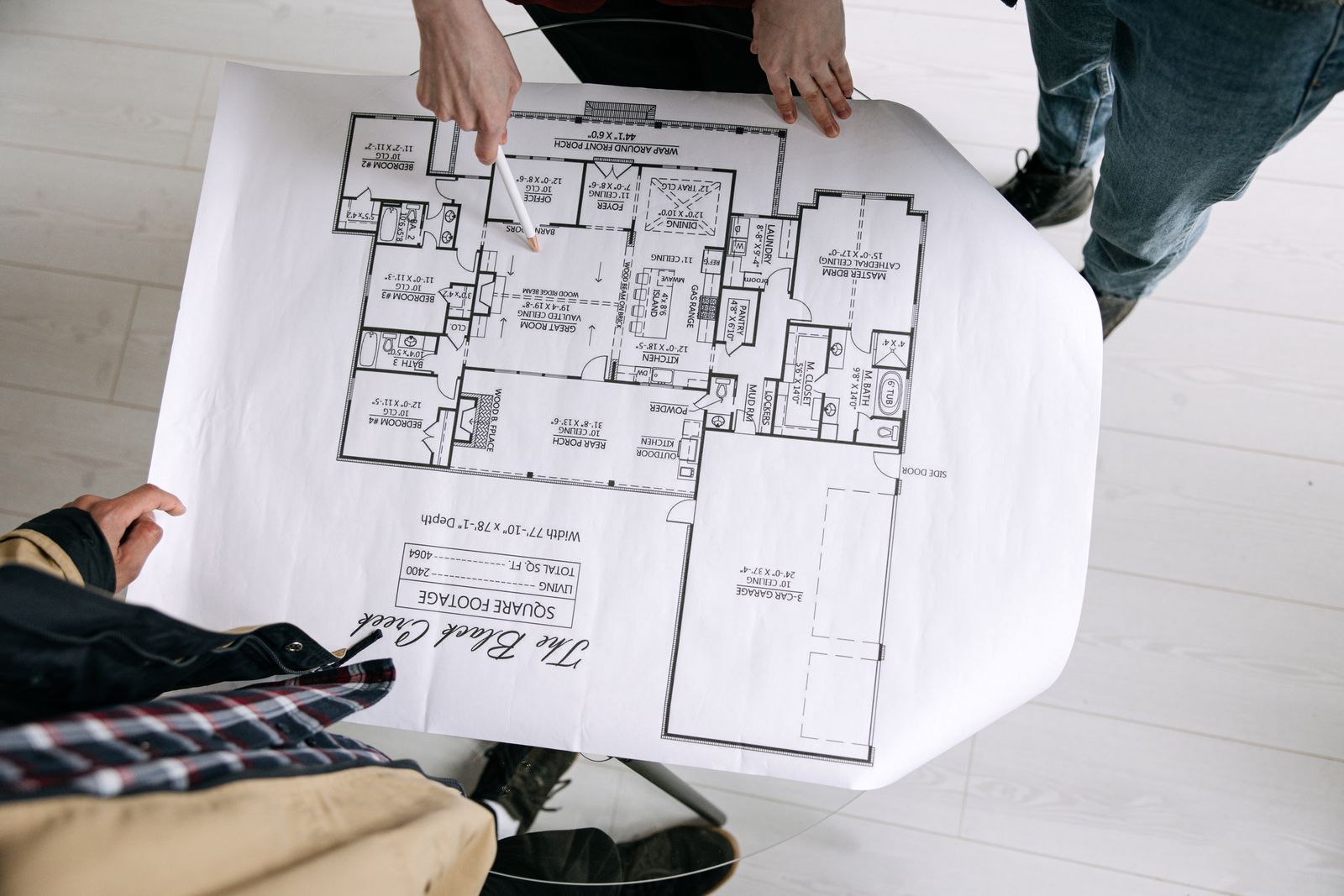 Two architects examining a detailed floor plan blueprint on a table indoors