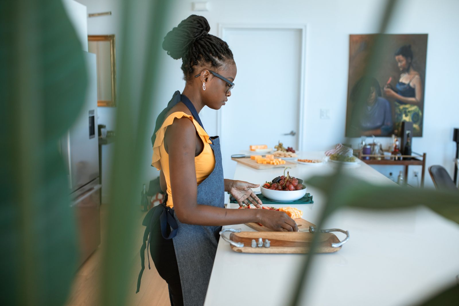 Black woman in an apron chopping vegetables on a kitchen counter