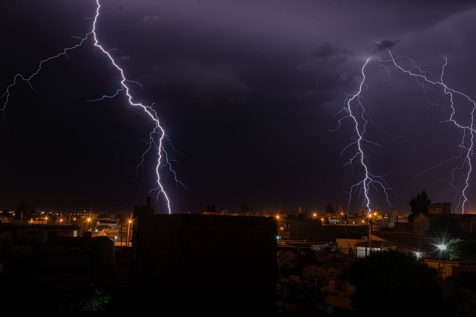 Intense lightning illuminates a city during a nighttime thunderstorm