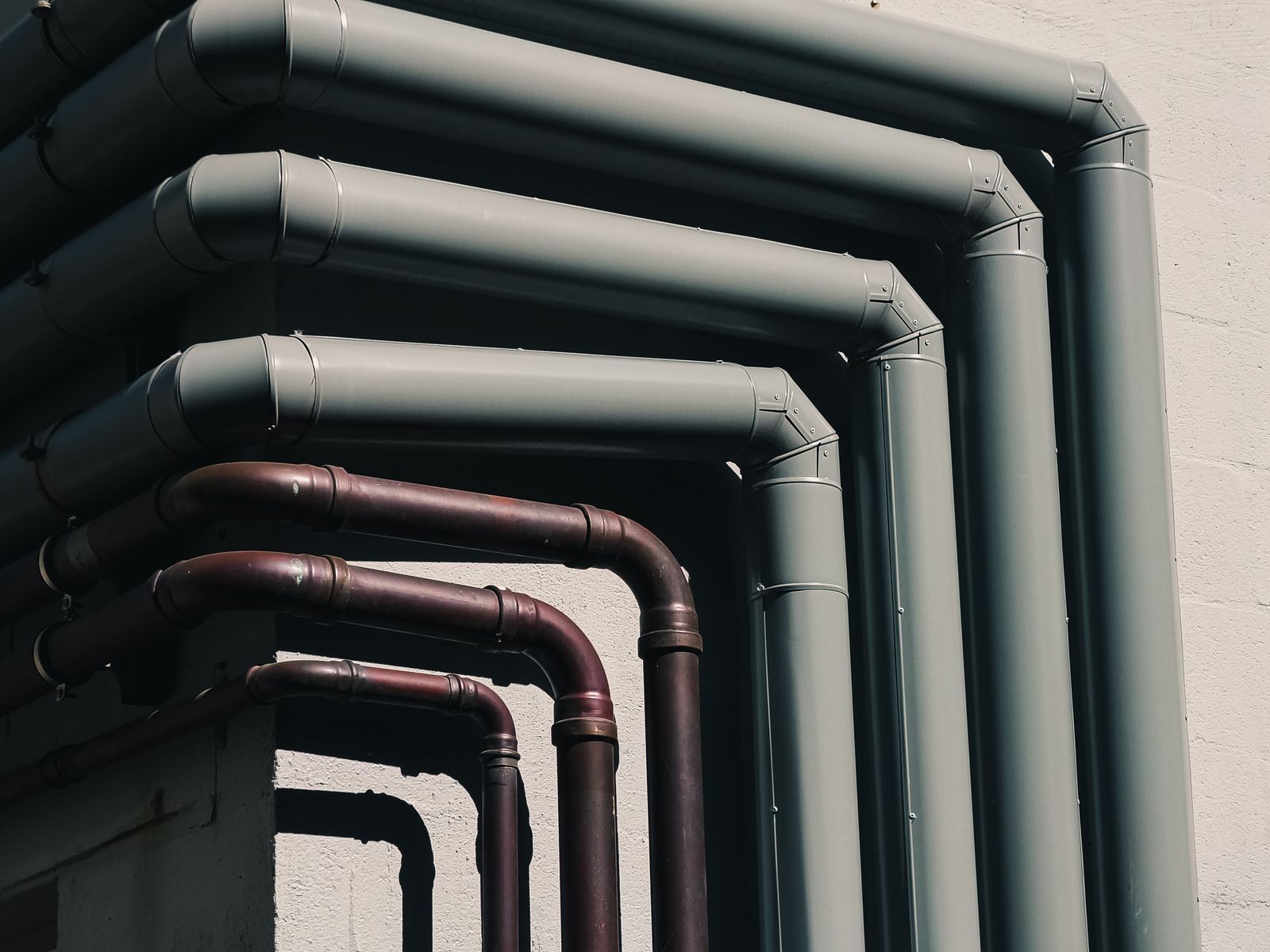 Close-up of industrial pipes forming a pattern on a building's exterior wall, shot outdoors
