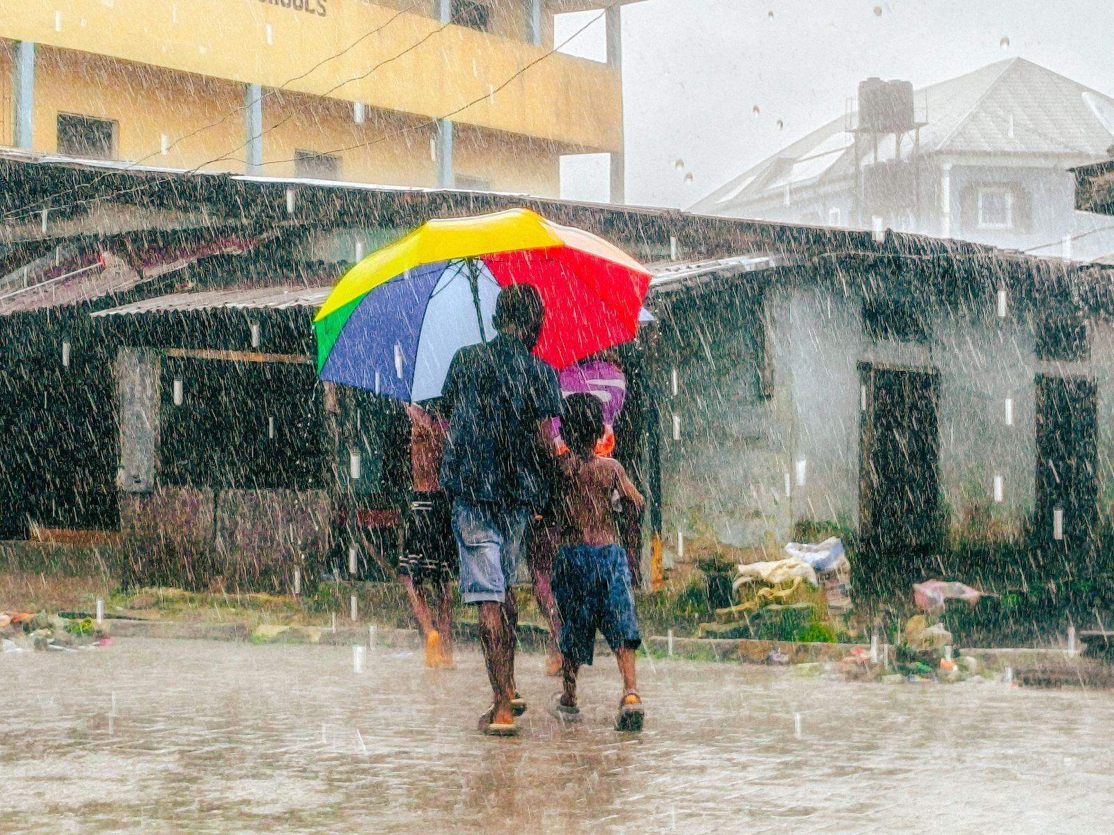 People walking under an umbrella on a street during heavy rain
