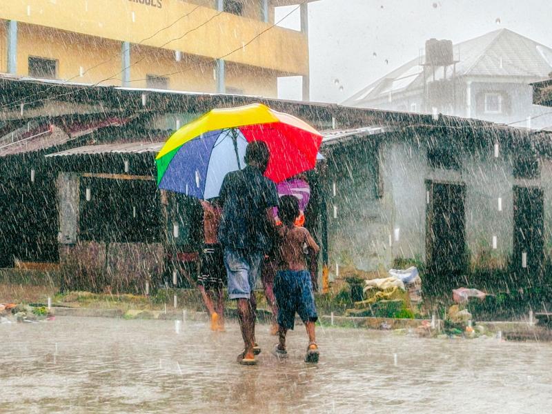People walking under an umbrella on a street during heavy rain