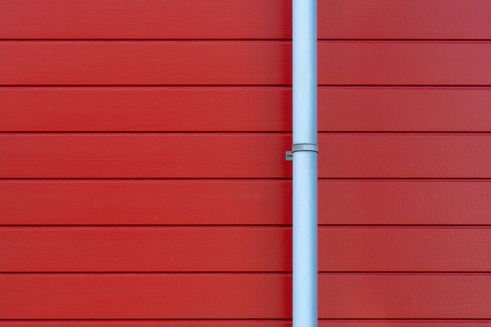 A red wall with a white rain gutter and downpipe