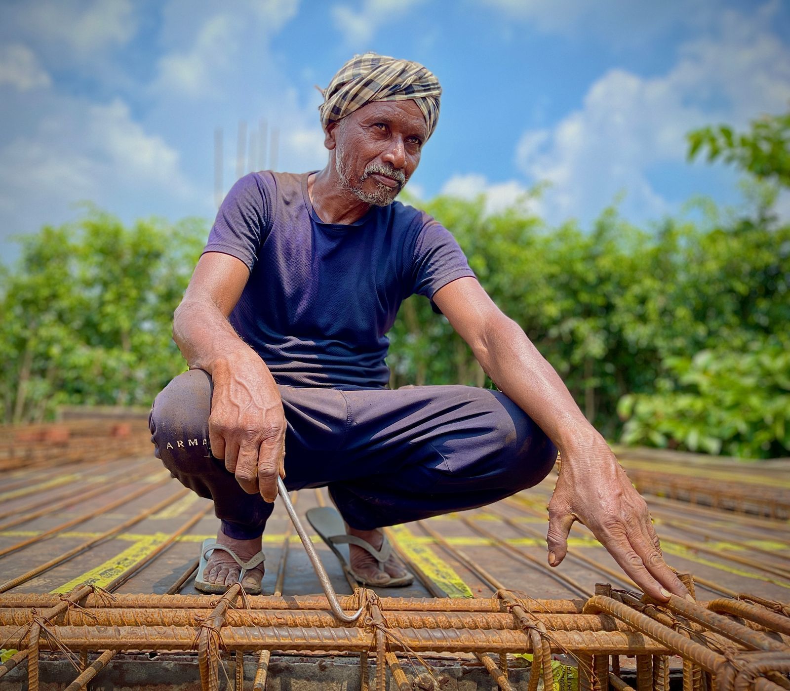 Elderly construction worker inspecting rebar framework on a sunny day