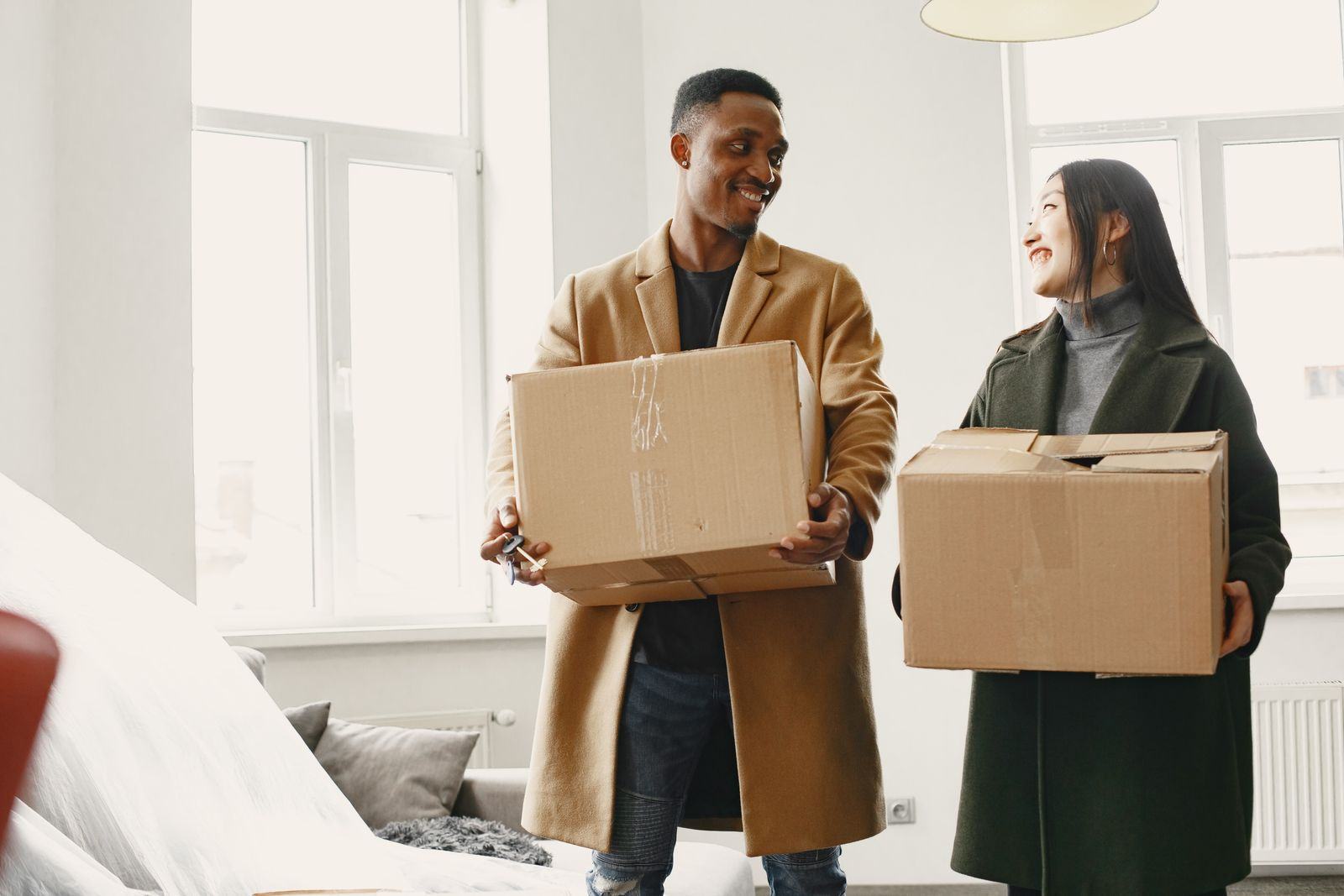 Couple carrying moving boxes into a new apartment
