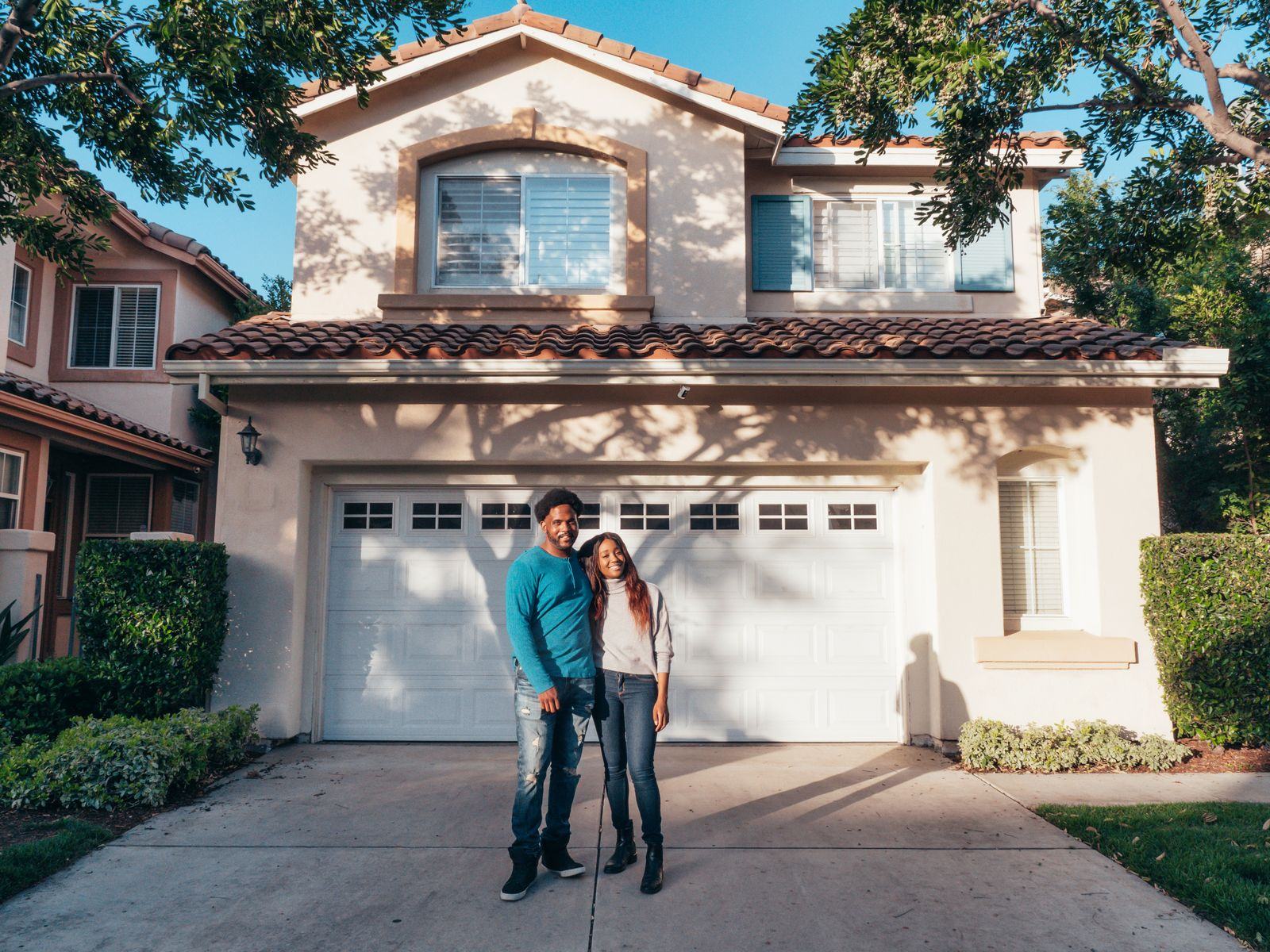 Couple standing in front of a house they own