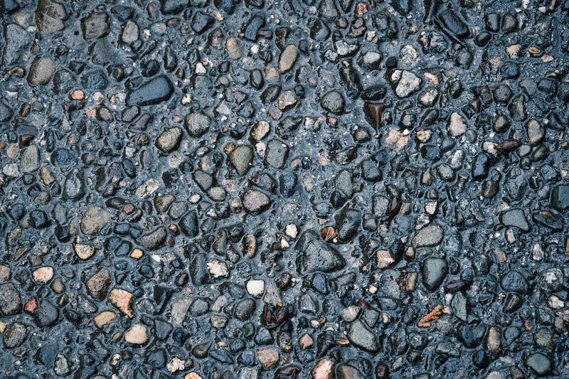 Detailed view of wet pebbled pavement revealing various shaped stones