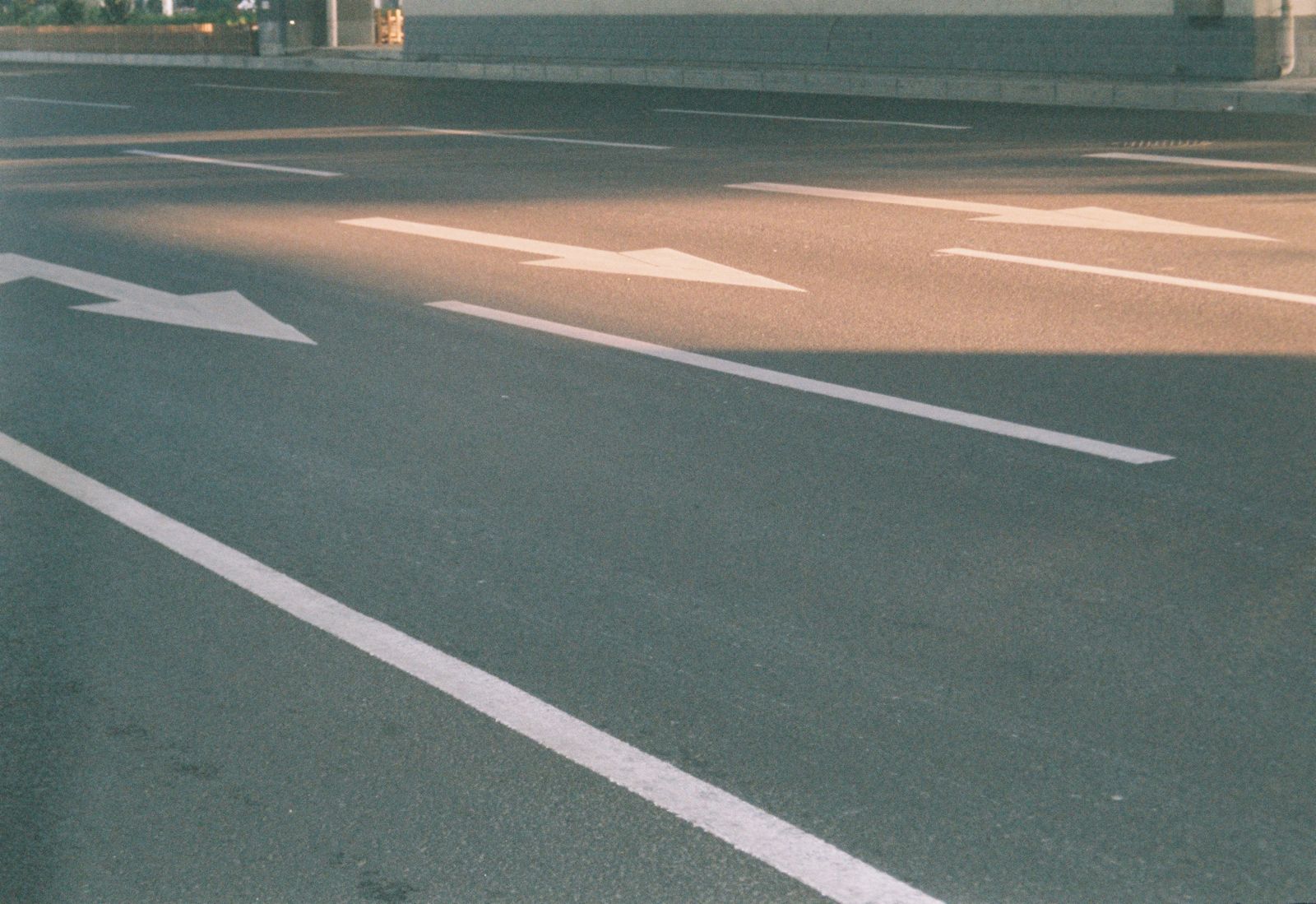 Photograph of a city street showing directional arrows on asphalt in sunlight