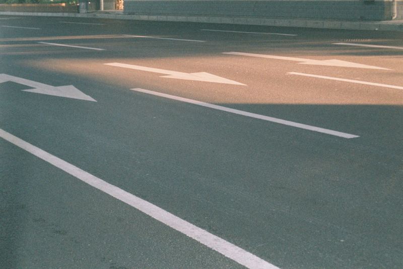 Photograph of a city street showing directional arrows on asphalt in sunlight