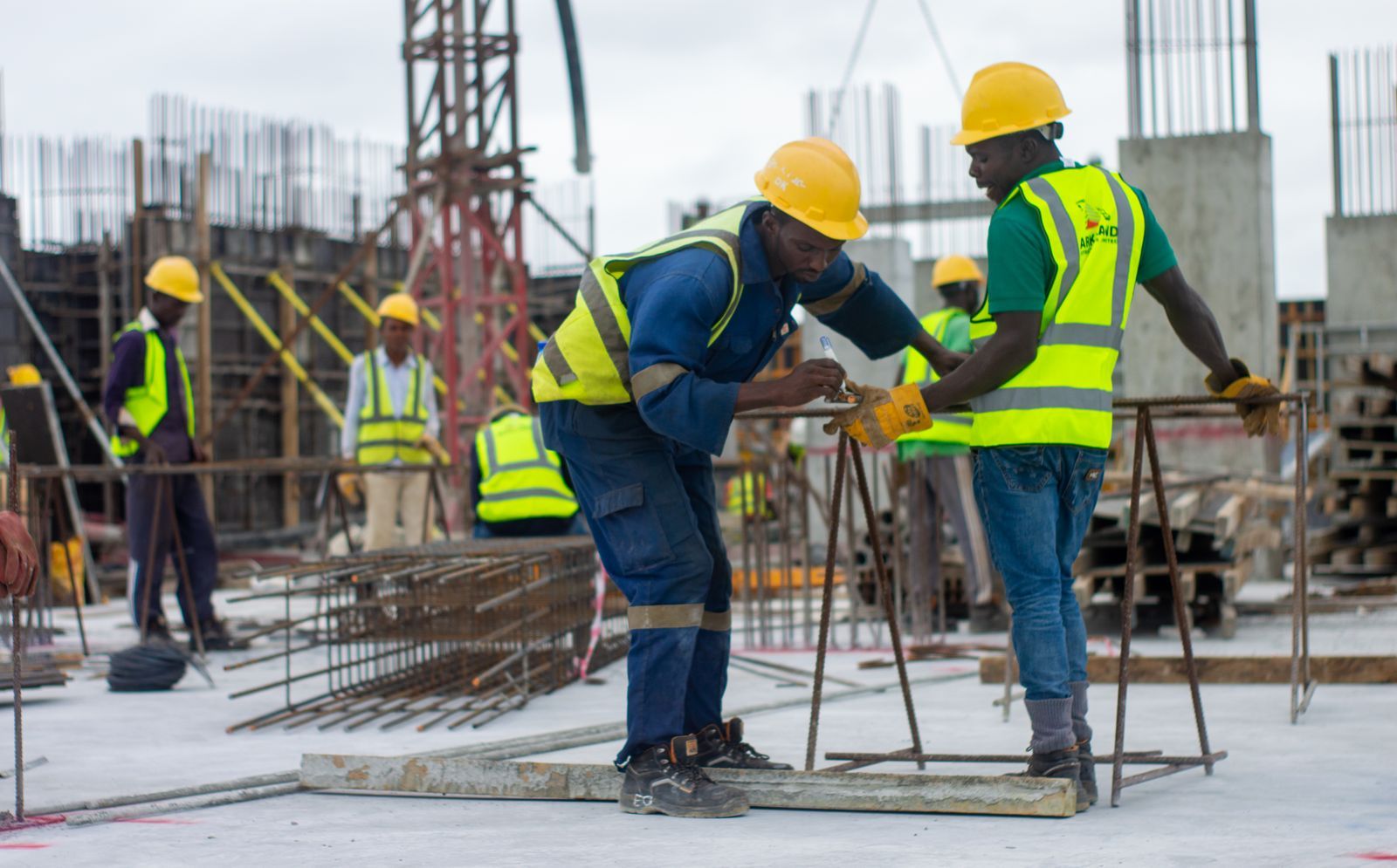 Construction workers in safety gear fixing steel on site