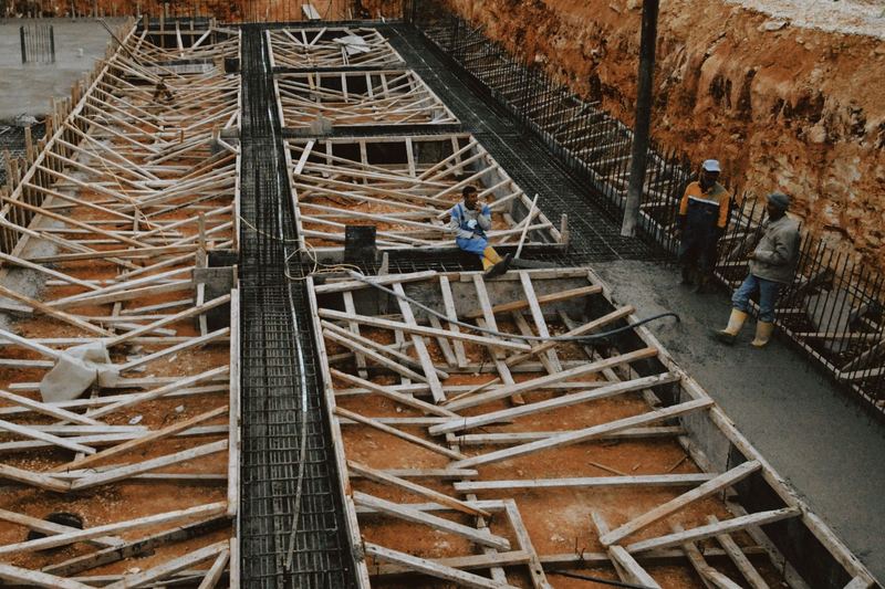 Construction workers at a site with wooden framework in progress