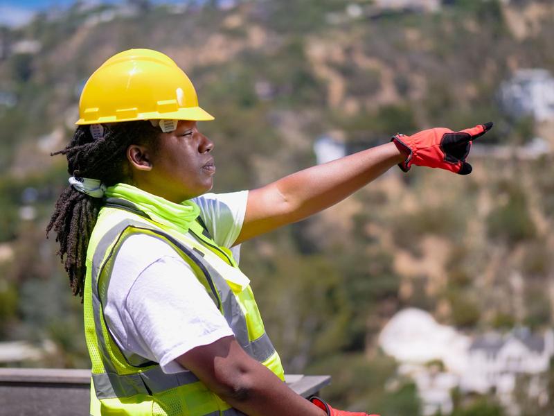 Woman engineer in a hard hat pointing across a construction site