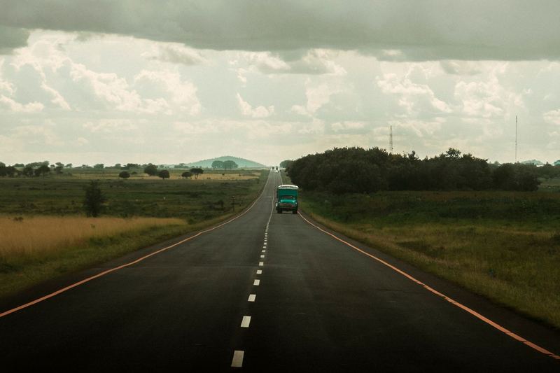An open road in Tanzania with a lone truck under a cloudy sky