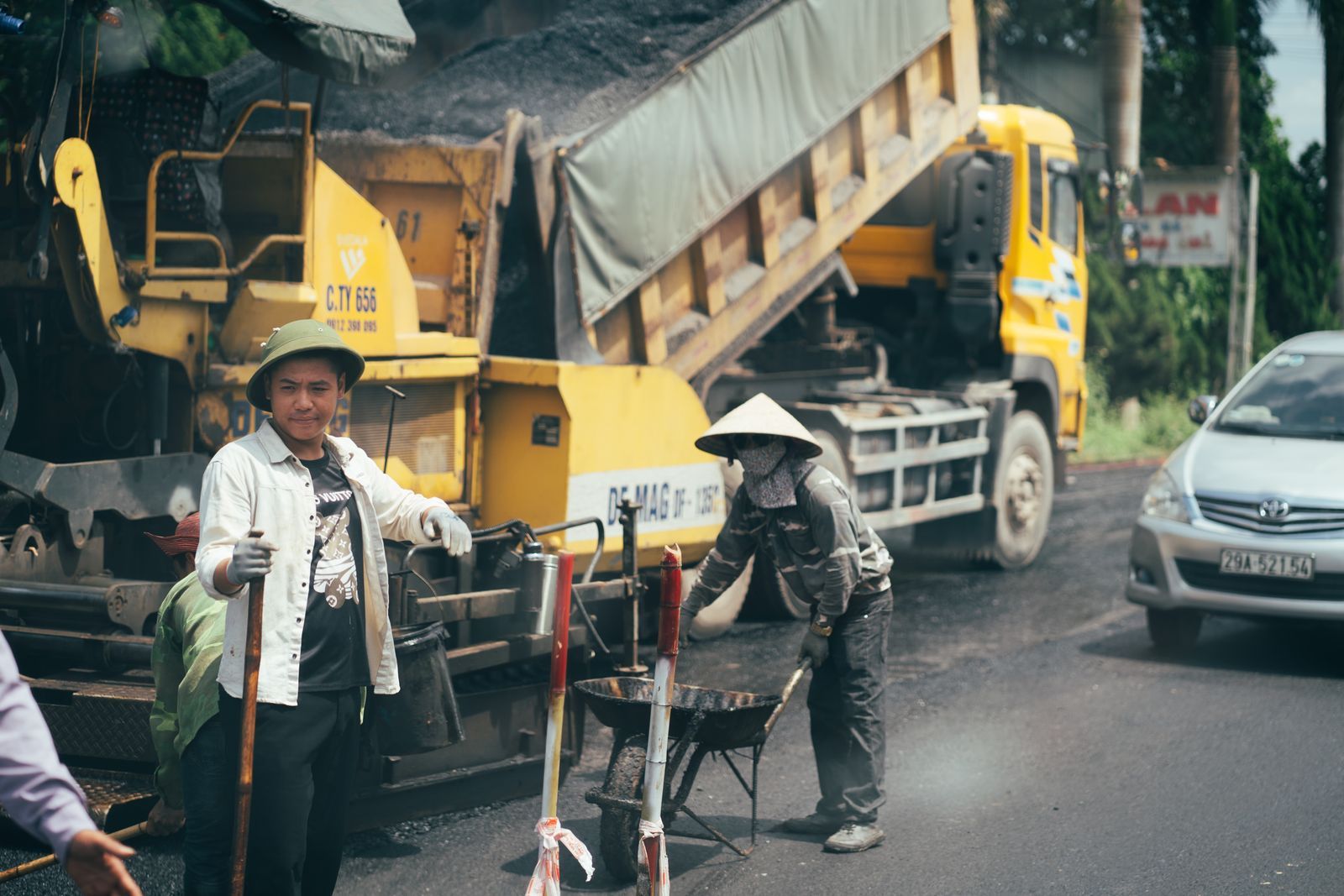 Men working on paving a road with construction machinery and vehicles