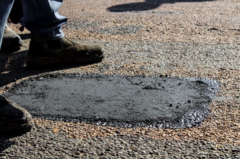 Close-up view of a freshly patched road section with work boots in South Africa